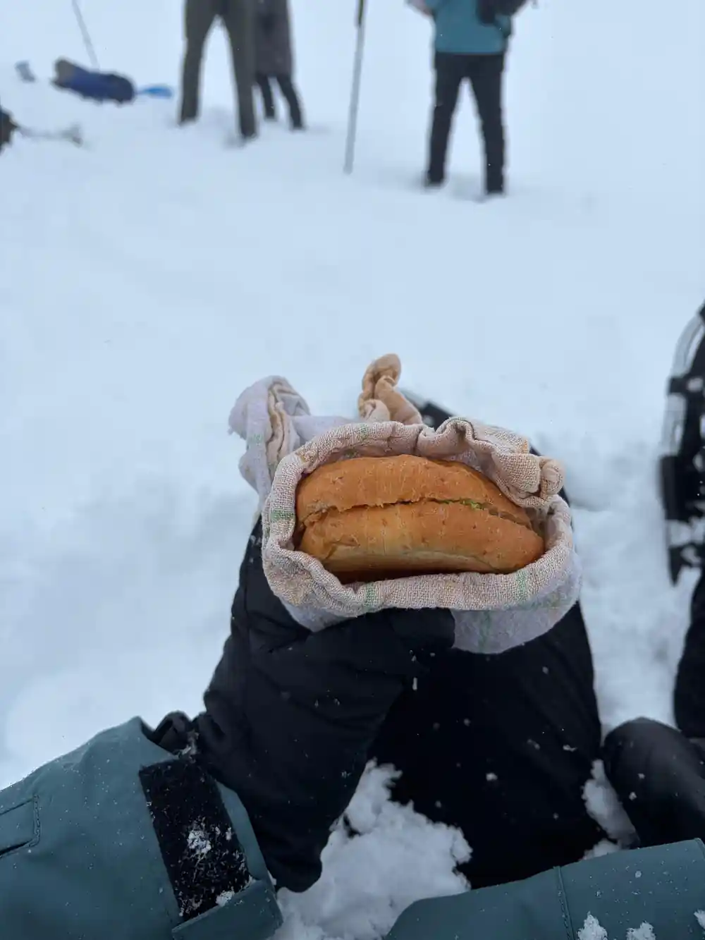A bread roll held in a mittened hand