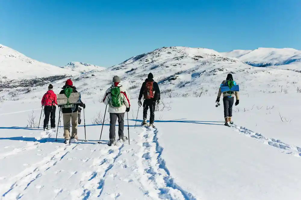 A group walking up a broad snow slope