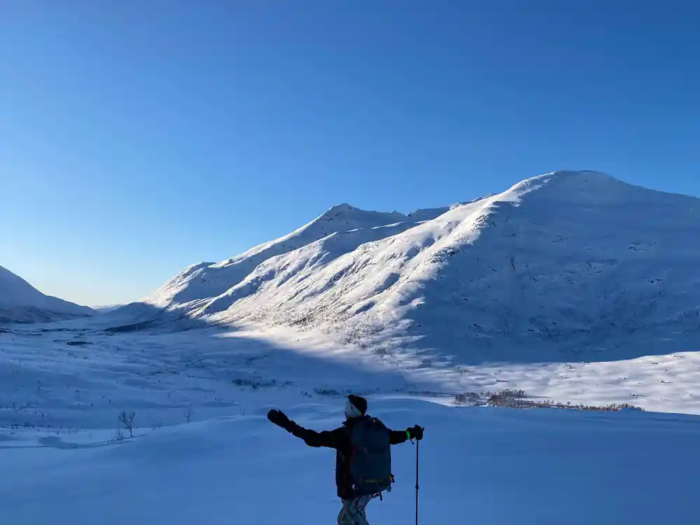 A lone walker with arms out below a great snow dome
