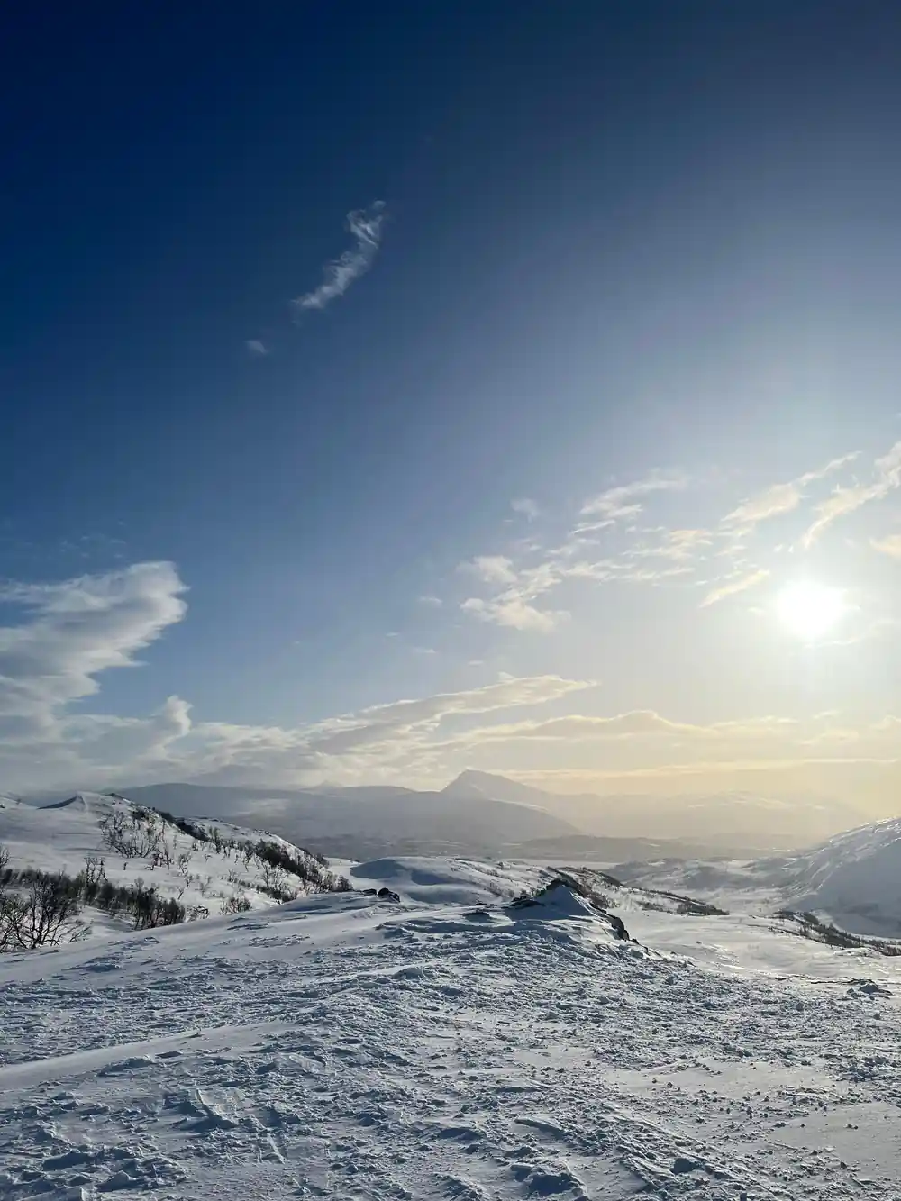 A pale sun low over a long white ridge