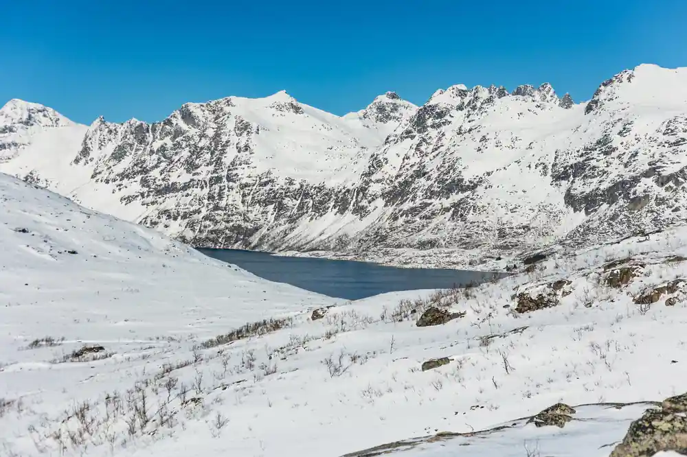 Snow peaks standing above the dark water