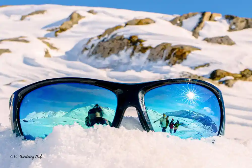 Sunglasses on the snow reflecting the group and the sun