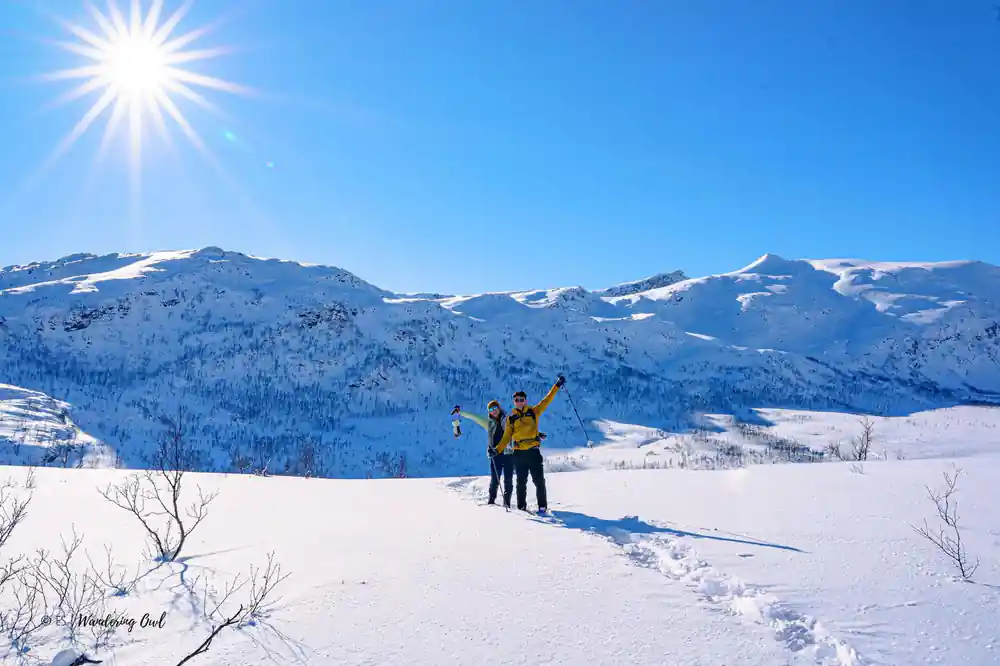 Two figures with arms raised on an empty snowfield