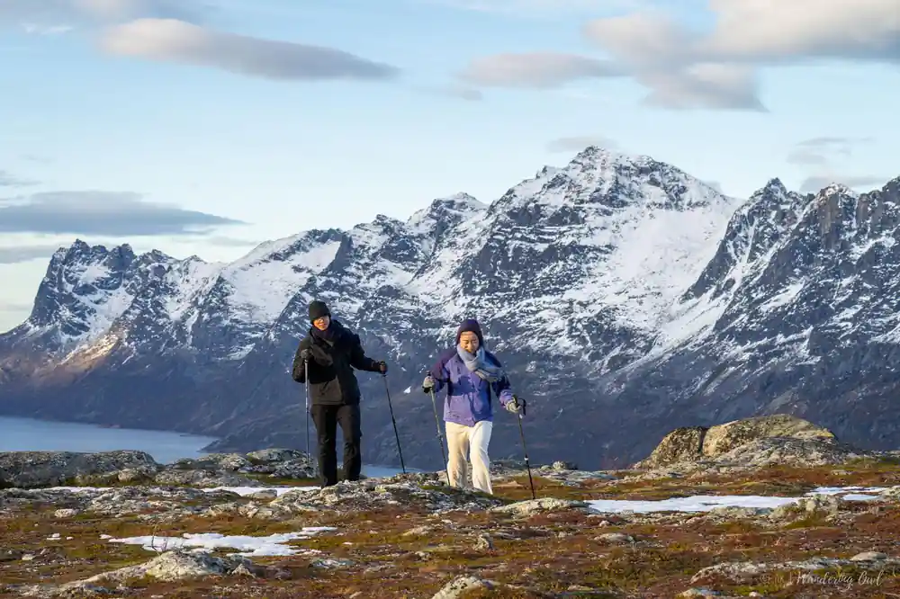 Two snowshoers on bare rock below the high peaks