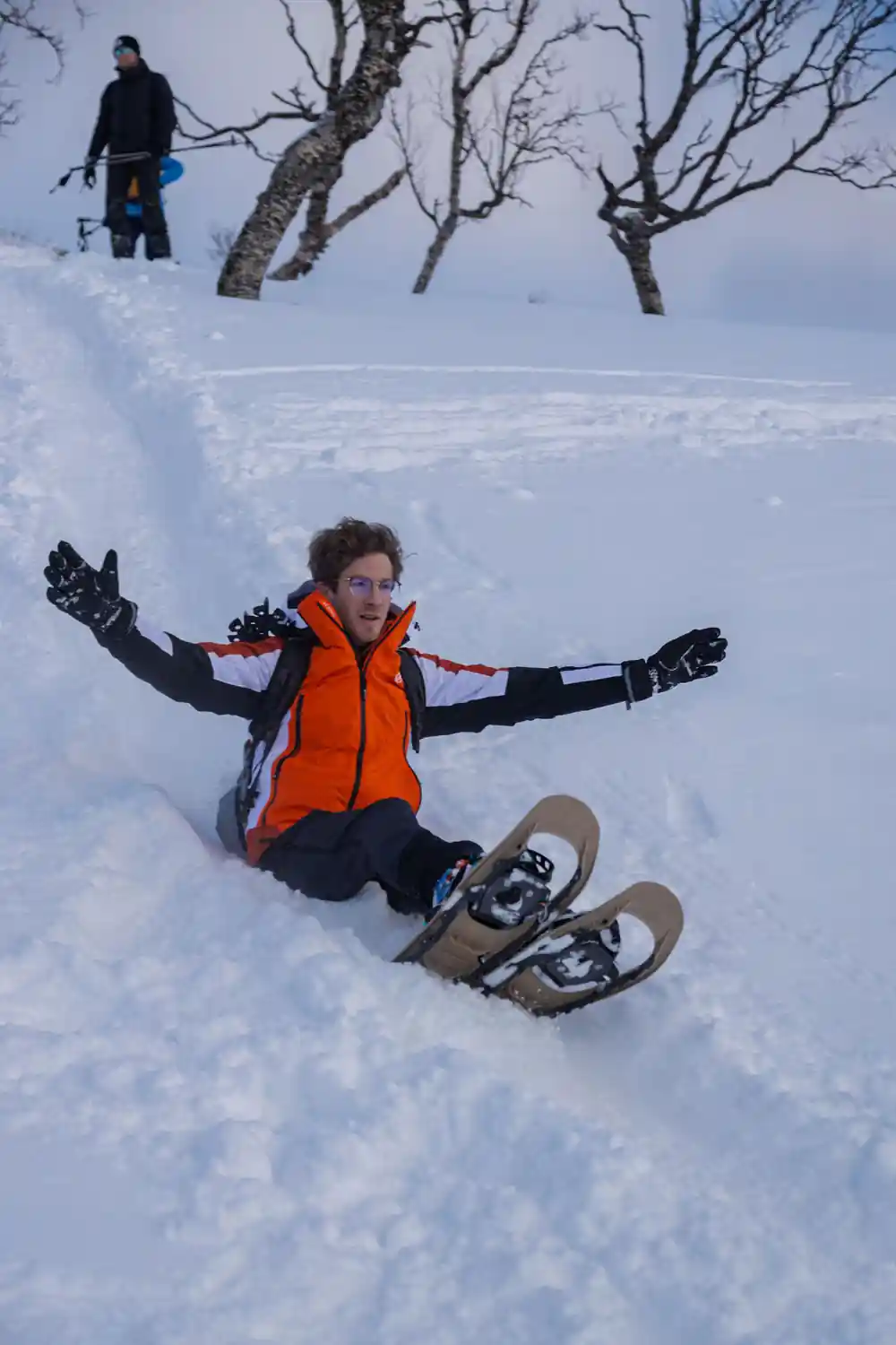 A walker sitting back in deep snow, snowshoes up